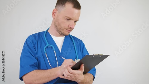 Wallpaper Mural The doctor fills out documents on the tablet. A man in a blue medical coat with a stethoscope around his neck on a white background Torontodigital.ca