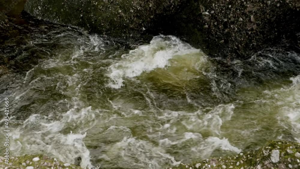 Dark, turbulent green whitewater flows down the North Esk River at the Rocks of Solitude in Scotland through a gorge. Dark, turbulent green whitewater flows down the North Esk River at the Rocks of Solitude in Scotland through a gorge.
