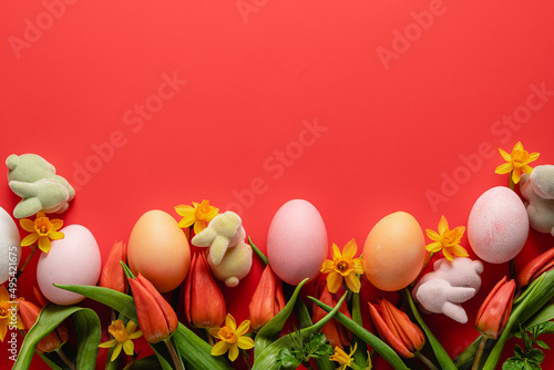 Easter holiday concept. Easter picture, multi-colored eggs, spring flowers on a red background. Happy Easter