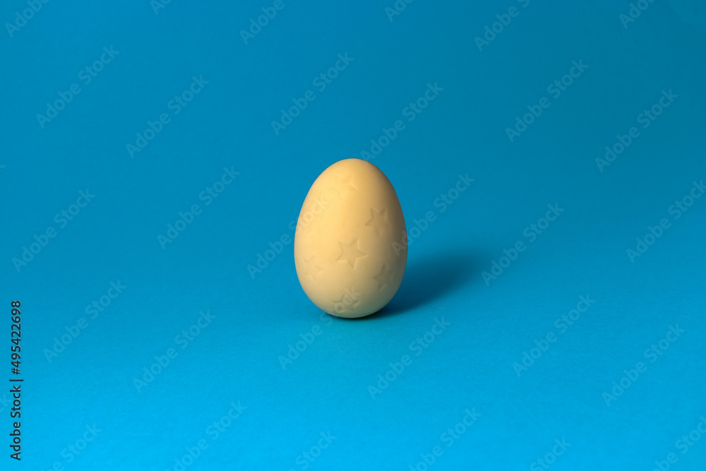 White chocolate with stars Easter egg on blue pastel pastel background. Close up. White chocolate with stars Easter egg on blue pastel pastel background. Close up.