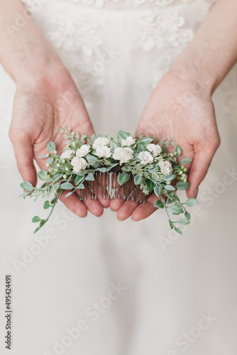 Wedding hair pin with white flowers in the hands of the bride close-up photo