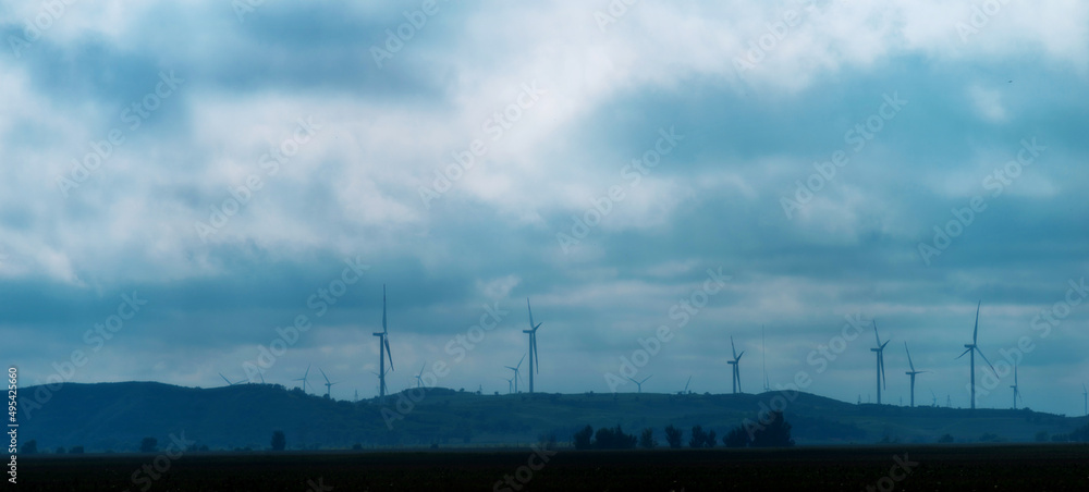 Windmill power on top of a hill with cloudy weather