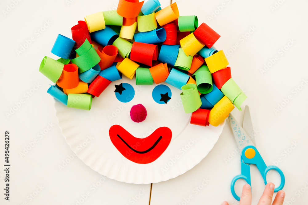 Paper plate clown. DIY games at home, activities for pre-school Kids. 5 minute crafts. Children joy and funny to cut a hair for clown. Red Nose Day theme.