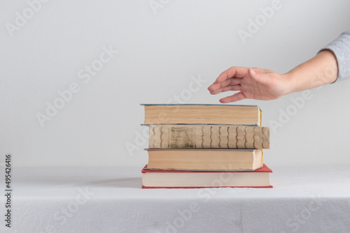 Stack of old rustic vintage books with the hand on white table 