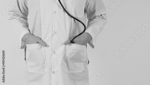 The doctor  hands in the pocket with a stethoscope. Hand wears the blue medical glove and a long-sleeve gown on white background. black and white photo.
