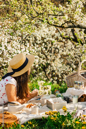 Breakfast picnic with waffles and tea in spring blossom garden on a white tablecloth on a sunny day, cherry blossoms. Outdoor, picnic, brunch, spring mood