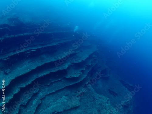 scuba divers around a reef underwater deep blue water big rock 