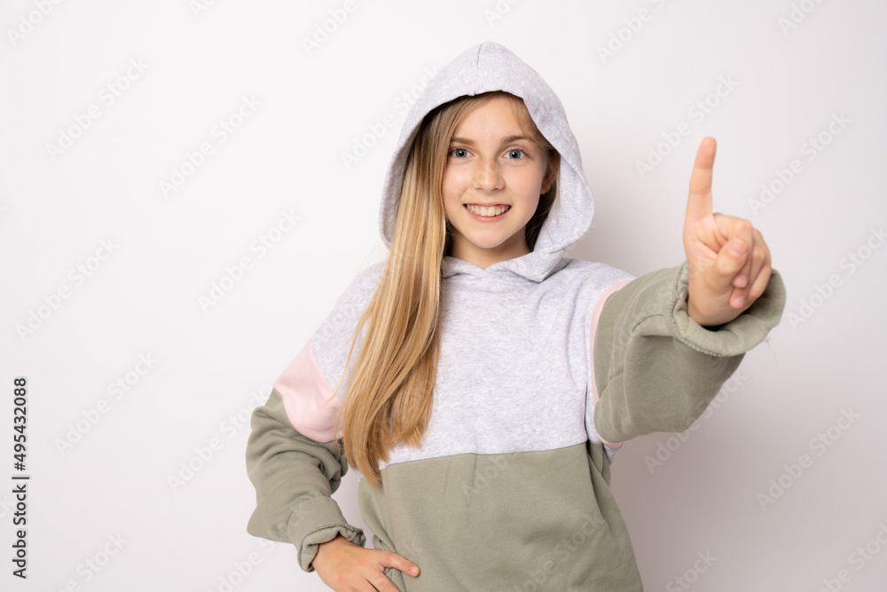 Beautiful little girl wearing casual clothes smiling and looking at the camera pointing finger up. Beautiful little girl wearing casual clothes smiling and looking at the camera pointing finger up.