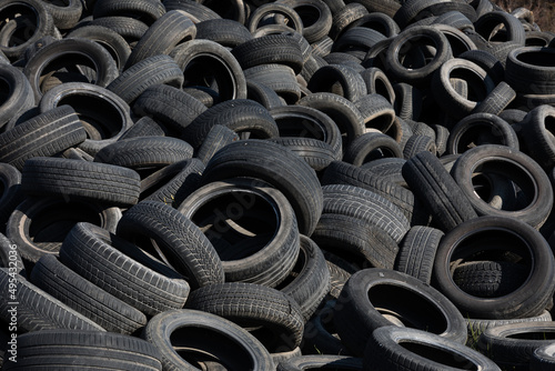 Landfill with old tires and tyres for recycling. Reuse of the waste rubber tyres. Disposal of waste tires. Worn out wheels for recycling. Regenerated tire rubber produced.