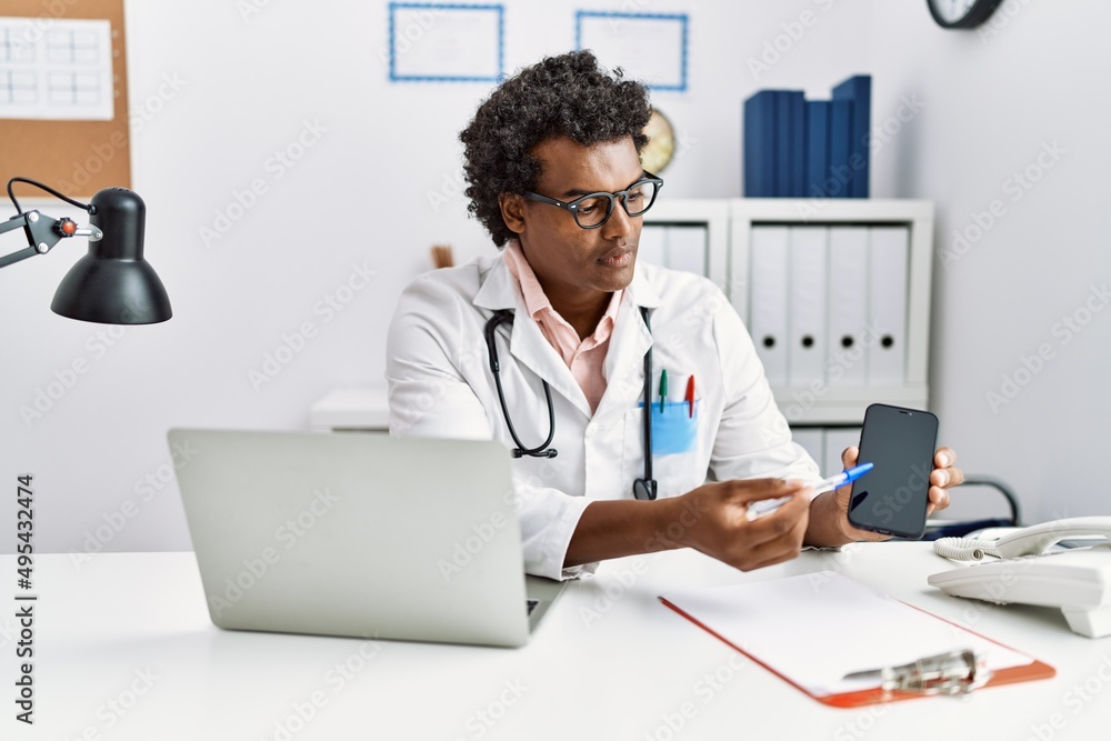 Young south east man wearing doctor uniform showing app medical smartphone at clinic Young south east man wearing doctor uniform showing app medical smartphone at clinic