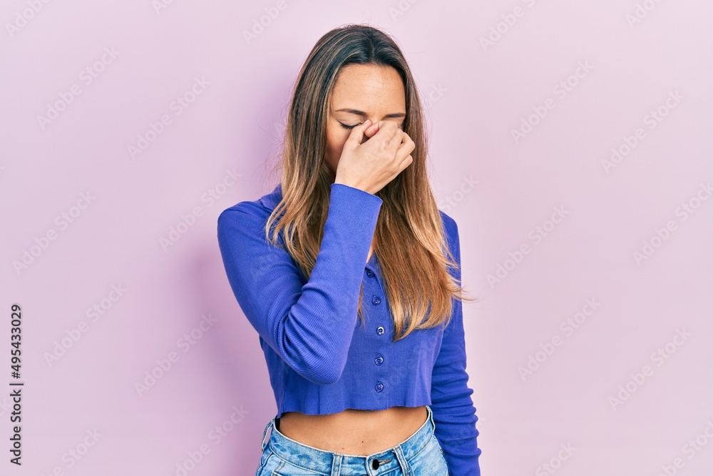 Beautiful hispanic woman wearing casual blue shirt tired rubbing nose and eyes feeling fatigue and headache. stress and frustration concept.