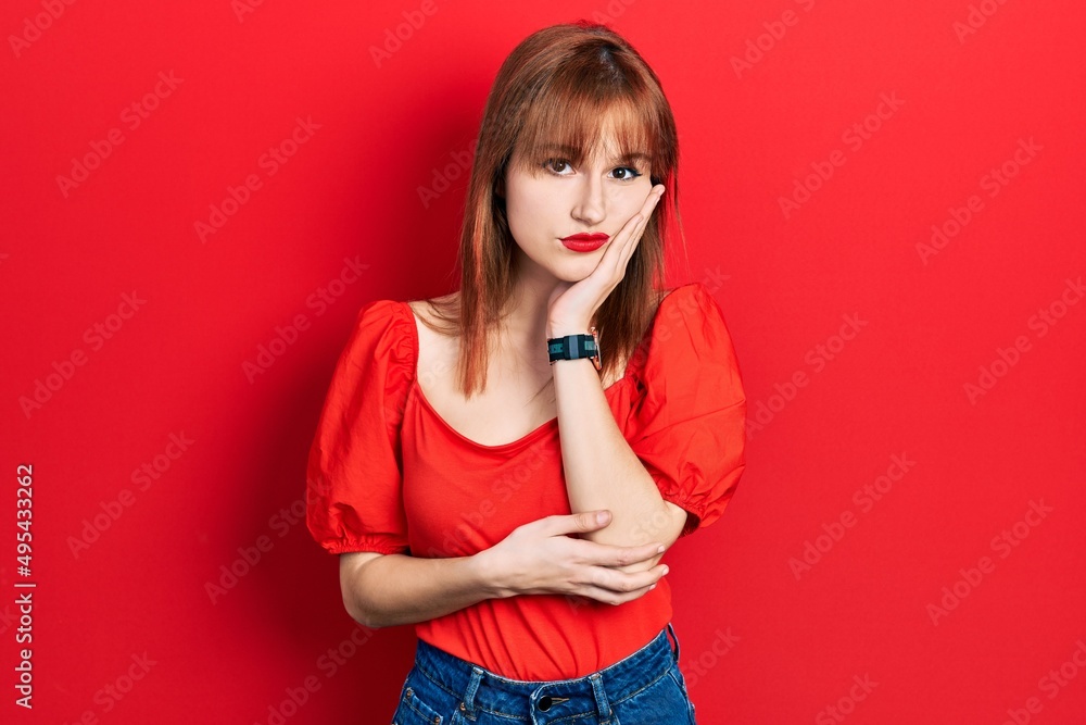 Redhead young woman wearing casual red t shirt thinking looking tired and bored with depression problems with crossed arms. Redhead young woman wearing casual red t shirt thinking looking tired and bored with depression problems with crossed arms.