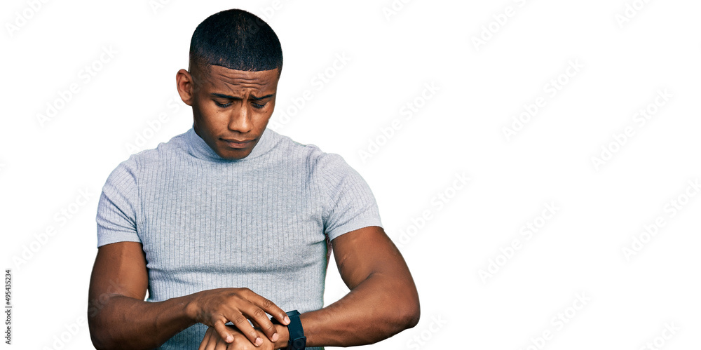 Young black man wearing casual t shirt checking the time on wrist watch, relaxed and confident Young black man wearing casual t shirt checking the time on wrist watch, relaxed and confident
