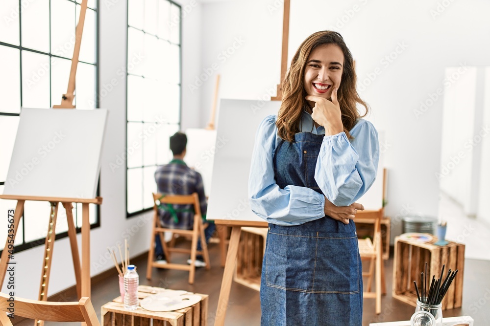 Young artist woman at art studio looking confident at the camera smiling with crossed arms and hand raised on chin. thinking positive. Young artist woman at art studio looking confident at the camera smiling with crossed arms and hand raised on chin. thinking positive.