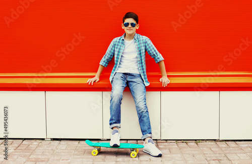 Portrait of teenager boy with skateboard on colorful red background