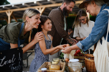 Happy woman buying organic eggs outdoors at local family farmers market.