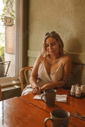 Blonde woman in light top sitting at table in a restaurant photo