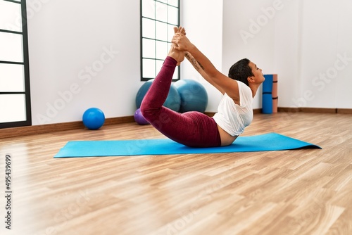 Young hispanic woman stretching at sport center