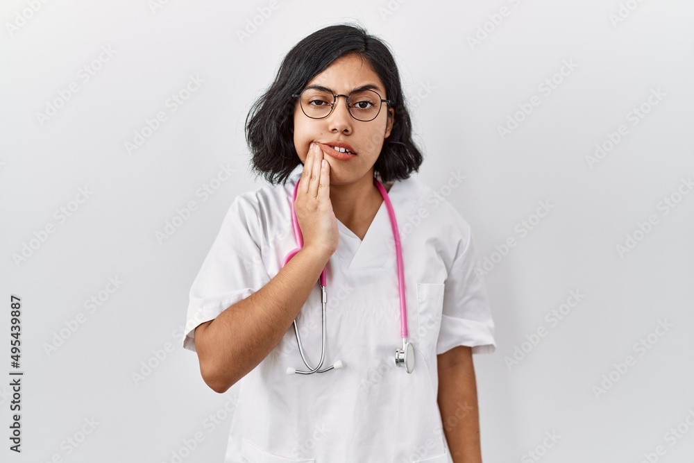 Young hispanic doctor woman wearing stethoscope over isolated background touching mouth with hand with painful expression because of toothache or dental illness on teeth. dentist Young hispanic doctor woman wearing stethoscope over isolated background touching mouth with hand with painful expression because of toothache or dental illness on teeth. dentist