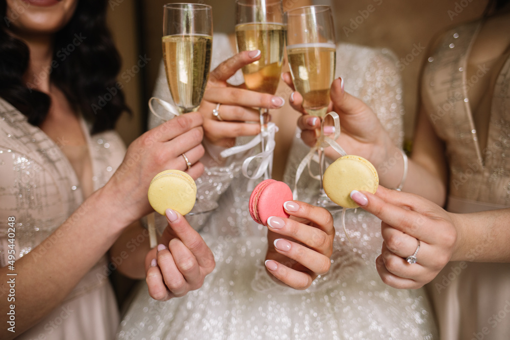 bright composition of macaroni, champagne in the hands of girls bright composition of macaroni, champagne in the hands of girls