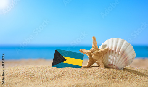 Tropical beach with seashells and Bahamas flag. The concept of a paradise vacation on the beaches of Bahamas.