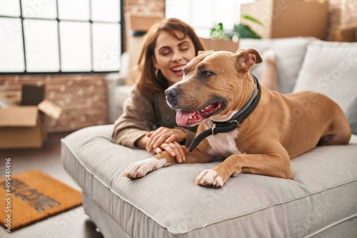 Young caucasian woman smiling confident lying on sofa with dog at new home