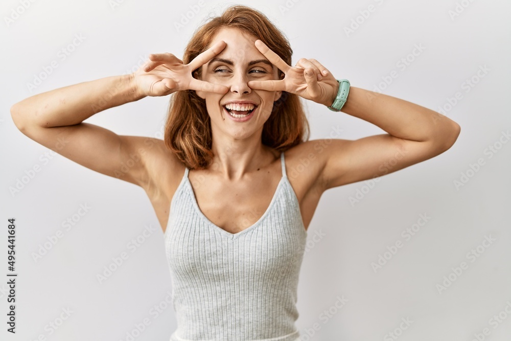 Beautiful caucasian woman standing over isolated background doing peace symbol with fingers over face, smiling cheerful showing victory Beautiful caucasian woman standing over isolated background doing peace symbol with fingers over face, smiling cheerful showing victory