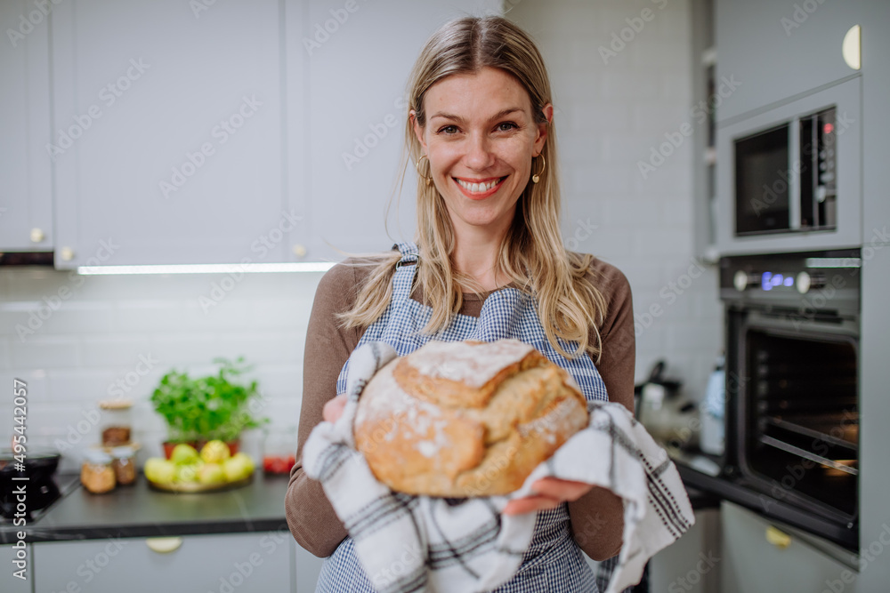 Happy woman holding homemade sourdough bread, cooking at home concept.
