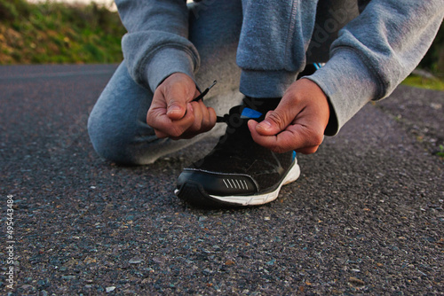 Person in gray sweater tying athletic shoes photo