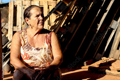 Portrait of an older woman sitting beside wooden wall outdoor photo