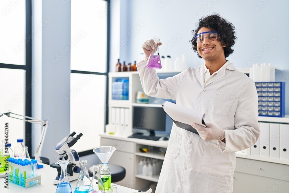Young hispanic man wearing scientist uniform holding clipboard and test  tube at laboratory Stock Photo | Adobe Stock