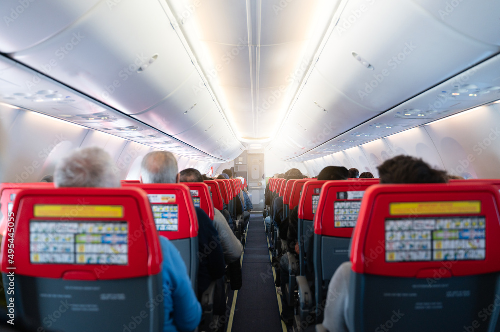 Plane aisle with copy space. Airplane full of passengers sit at their seats.
