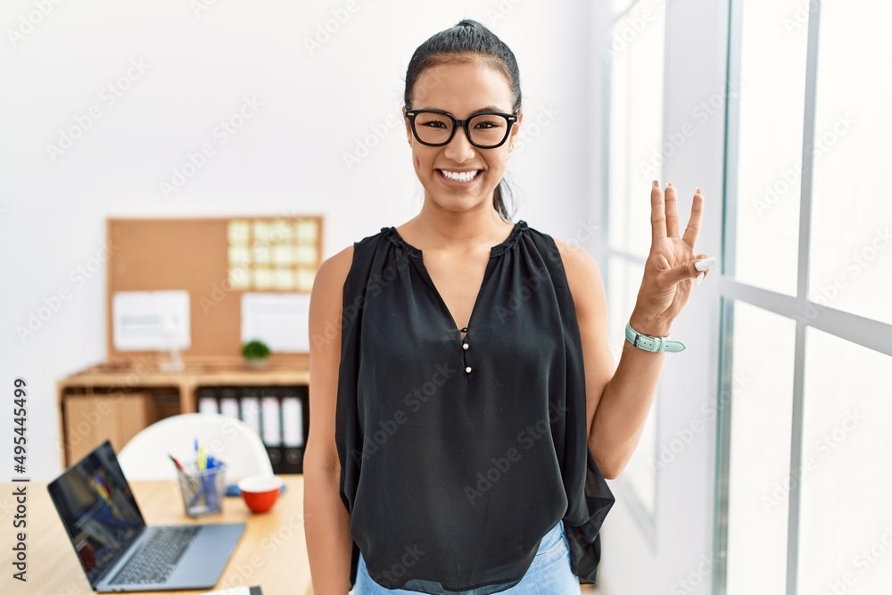 Young hispanic business woman working at the office showing and pointing up with fingers number three while smiling confident and happy. Young hispanic business woman working at the office showing and pointing up with fingers number three while smiling confident and happy.