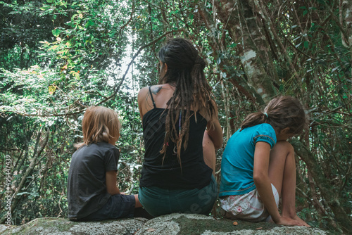 Woman and two children sitting on rock in forest