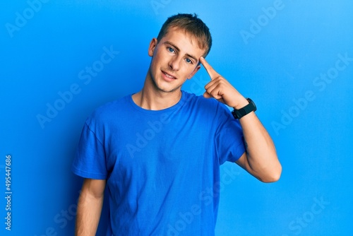 Young caucasian man wearing casual blue t shirt smiling pointing to head with one finger, great idea or thought, good memory