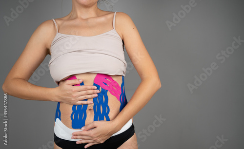 Unknown woman shows her belly with physio tape. The theme kinesiology taping, stretching, recovery concept