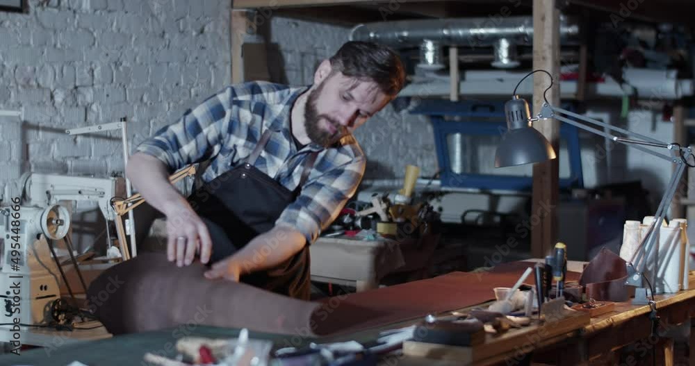 Male artisan rolling leather in workshop