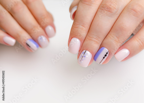 The hand of a young woman with soft pink, lilac gel polish and abstract design. Manicure Ideas