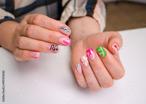 The hands of a young woman. The nails are covered with a light gel polish with a color design. Manicure Ideas