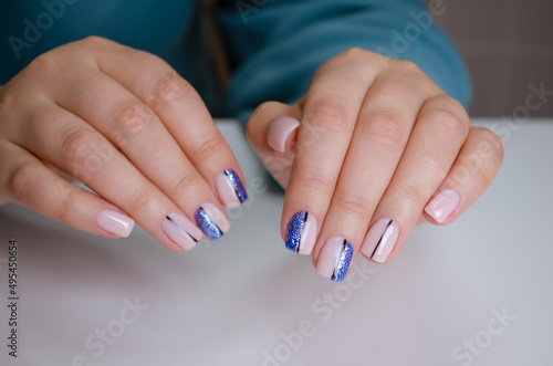 The hand of a young woman with soft pink, blue gel polish and abstract design. Manicure Ideas