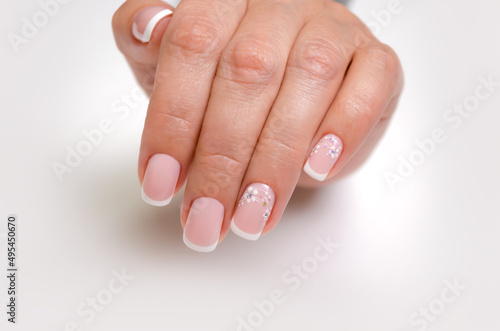 The hand of a young woman with a french manicure and design