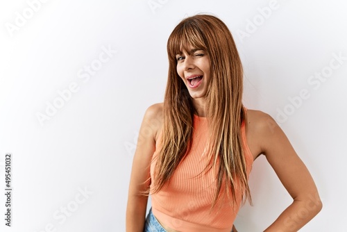 Hispanic woman with bang hairstyle standing over isolated background looking away to side with smile on face, natural expression. laughing confident.