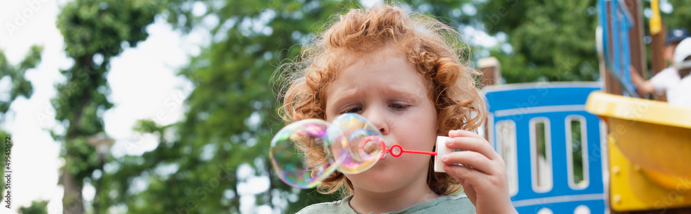 boy blowing soap bubbles outdoors in park, banner. boy blowing soap bubbles outdoors in park, banner.