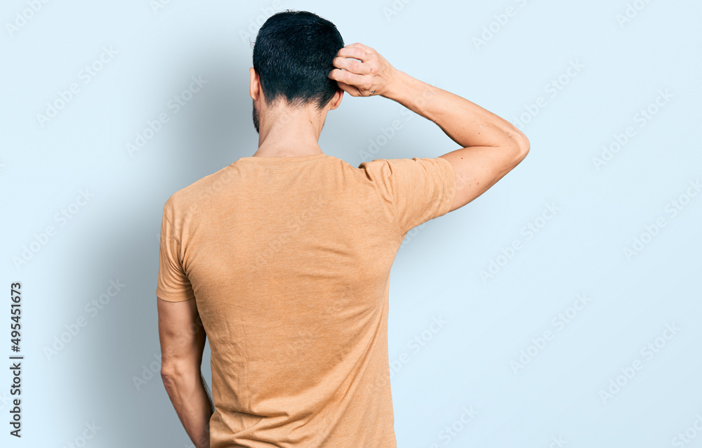 Hispanic man with beard wearing casual t shirt backwards thinking about doubt with hand on head Hispanic man with beard wearing casual t shirt backwards thinking about doubt with hand on head