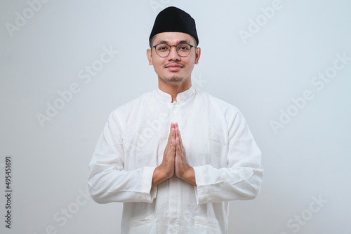 Asian Muslim man wearing glasses smiling to give greeting during Ramadan and Eid Al Fitr celebration photo