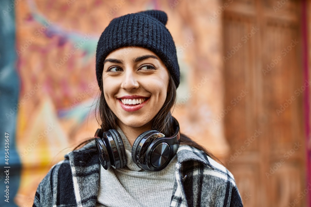 Young hispanic woman smiling happy using headphones at the city. Young hispanic woman smiling happy using headphones at the city.