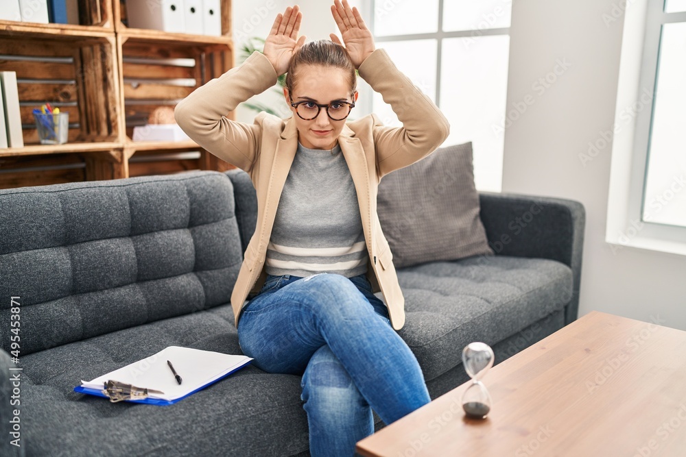 Young woman working at consultation office doing bunny ears gesture with hands palms looking cynical and skeptical. easter rabbit concept. Young woman working at consultation office doing bunny ears gesture with hands palms looking cynical and skeptical. easter rabbit concept.