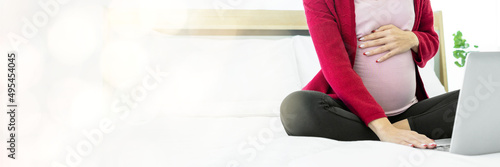 pregnant woman Searching for information for pregnant women on the internet with her laptop in the bedroom web banner with copy space on left