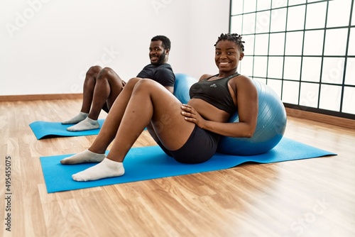 Young african american sporty couple smiling happy training pilates using fitball at sport center.