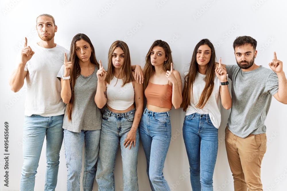 Group of young friends standing together over isolated background pointing up looking sad and upset, indicating direction with fingers, unhappy and depressed. Group of young friends standing together over isolated background pointing up looking sad and upset, indicating direction with fingers, unhappy and depressed.